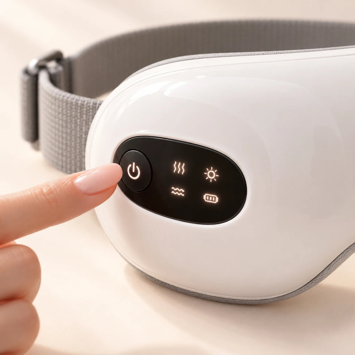 Dedo pulsando el botón del panel de control de las gafas de masaje para ojos